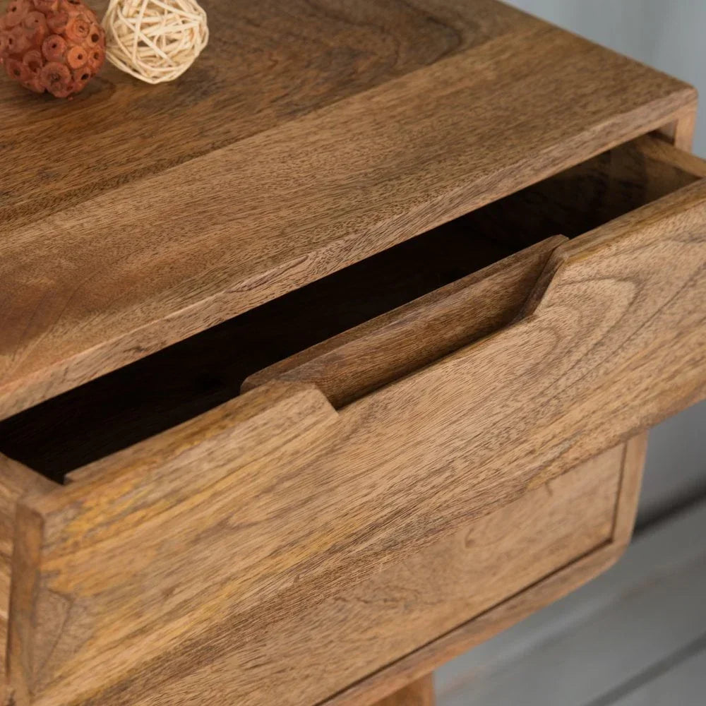 Close-up of wooden drawer unit with open drawer and decorative balls on top surface