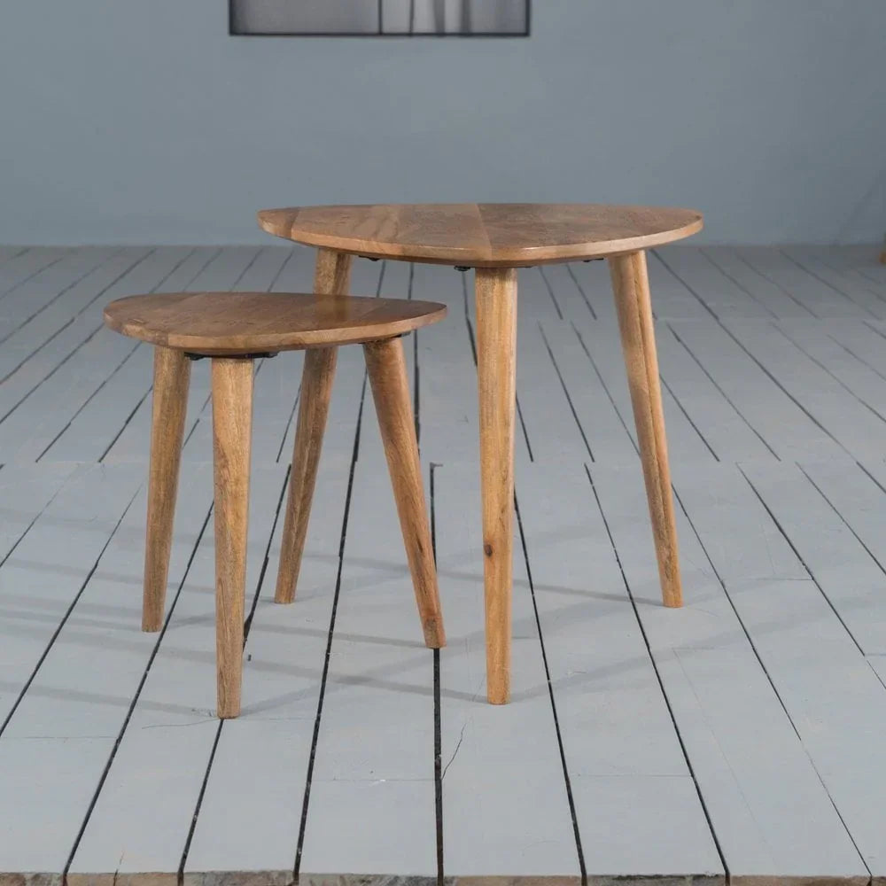 Set of two wooden nesting tables with round tops and angled legs on painted floor
