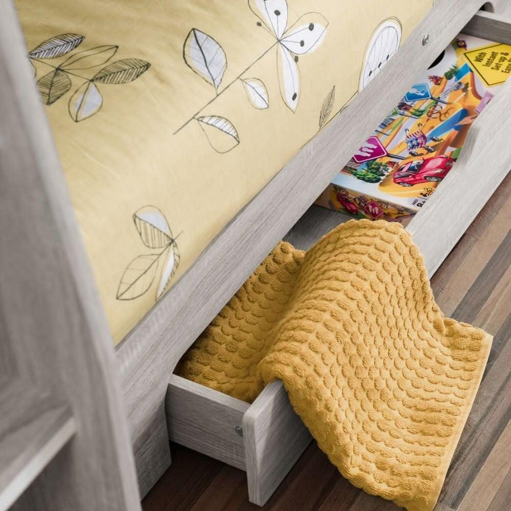 Light wood storage bed with yellow blanket in underbed drawer and printed bedding