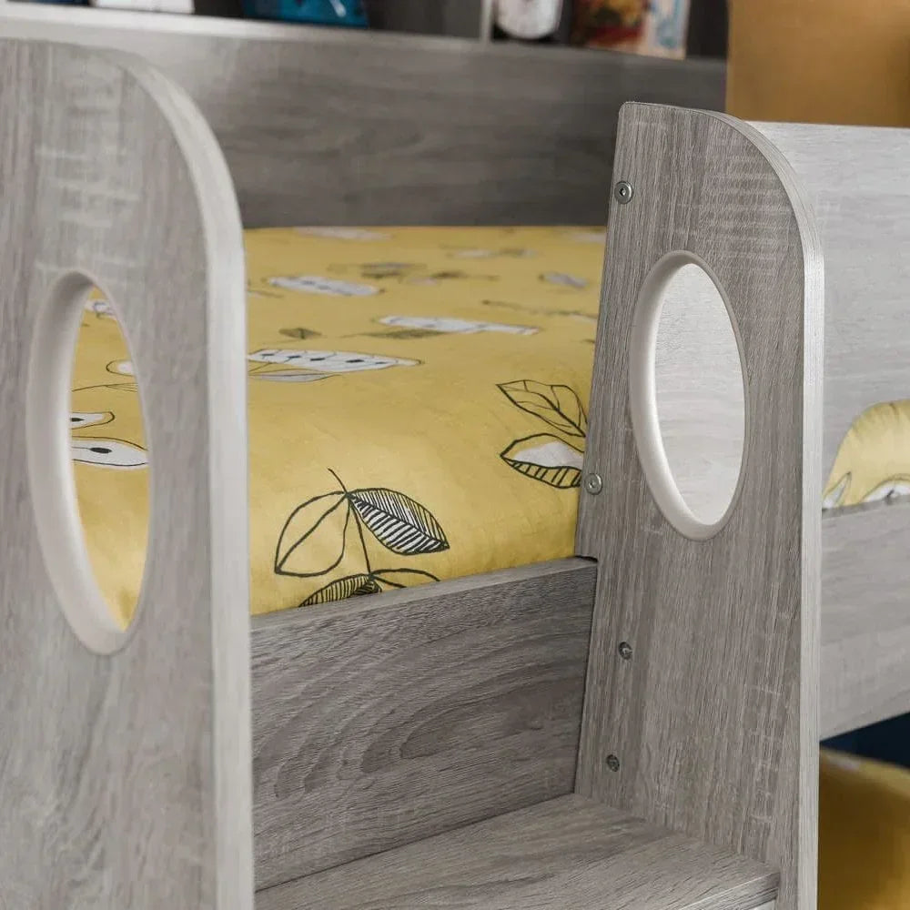 Grey wood bunk bed frame with circular cutouts and yellow leaf print bedding