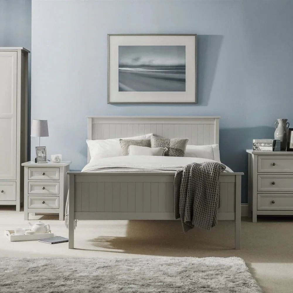 Grey wooden bed frame with bedding, bedside tables, and wardrobe in modern bedroom