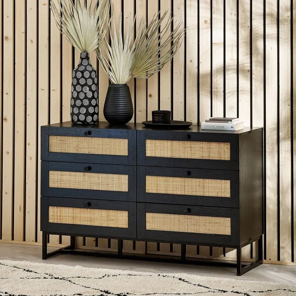 Black wood sideboard with rattan drawers, styled with vases and books, on modern rug