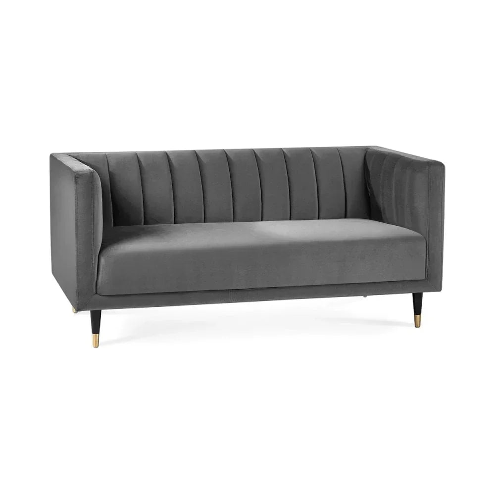 Grey velvet sofa with vertical tufted backrest and gold-tipped angled legs on white background