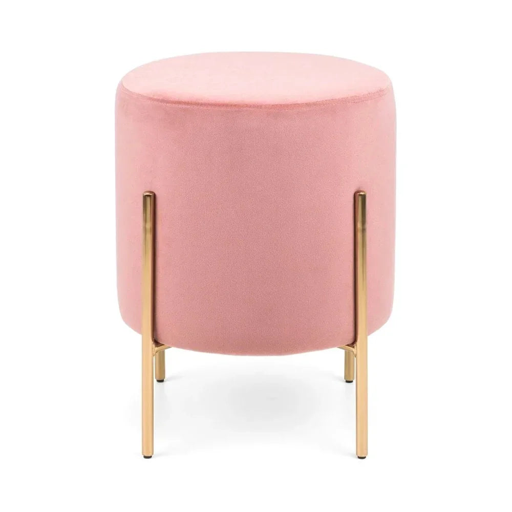 Pink velvet footstool with round seat and gold metal legs against white background