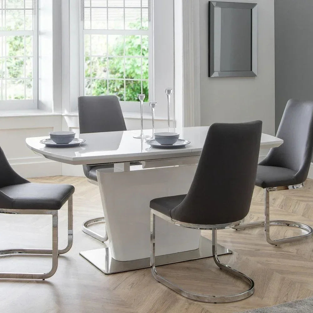 White gloss dining table with four grey faux leather chairs in a bright modern room