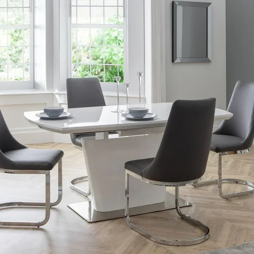 Gloss white dining table with four grey chrome chairs in bright modern dining room