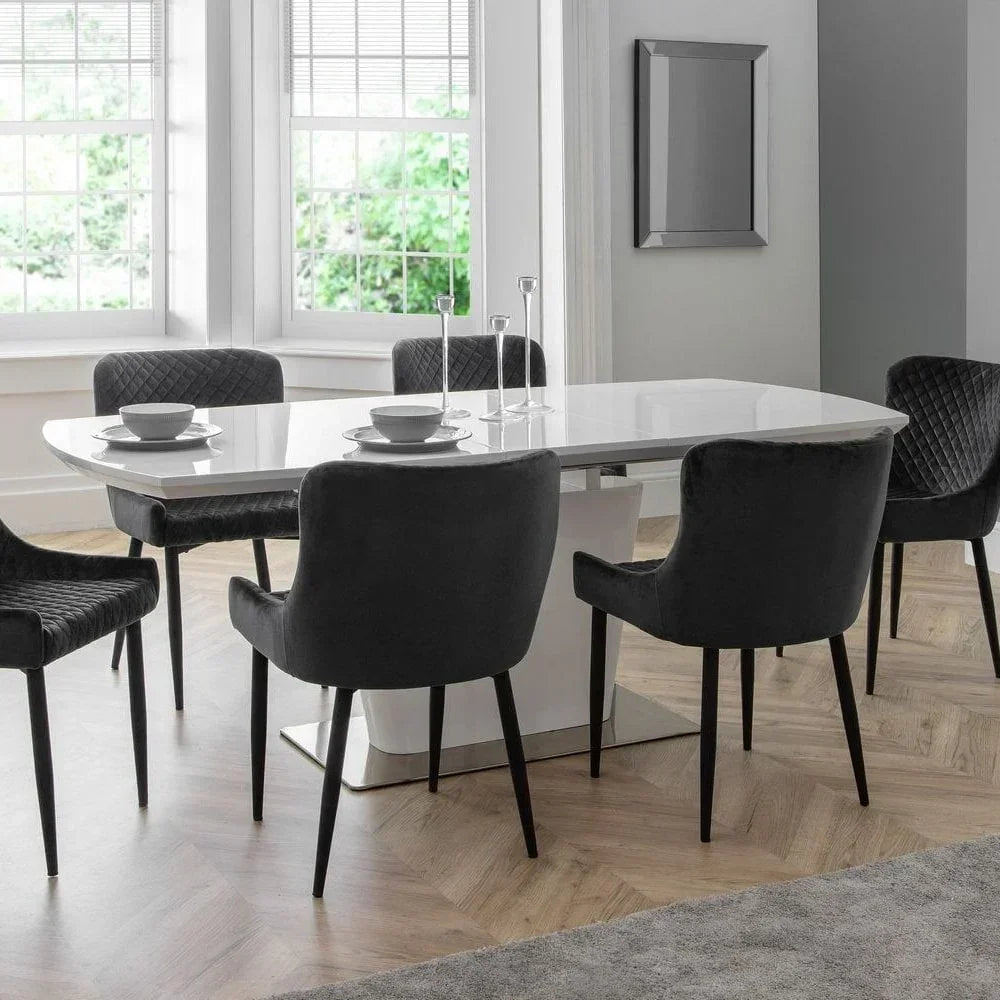 White gloss dining table with six dark grey velvet chairs in a modern dining room
