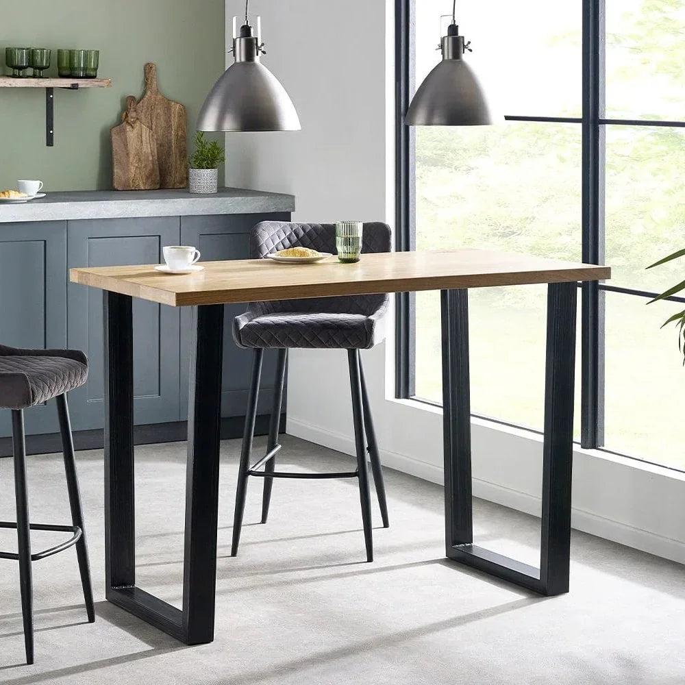 Wood bar table with black metal legs and grey bar stools in modern kitchen setting
