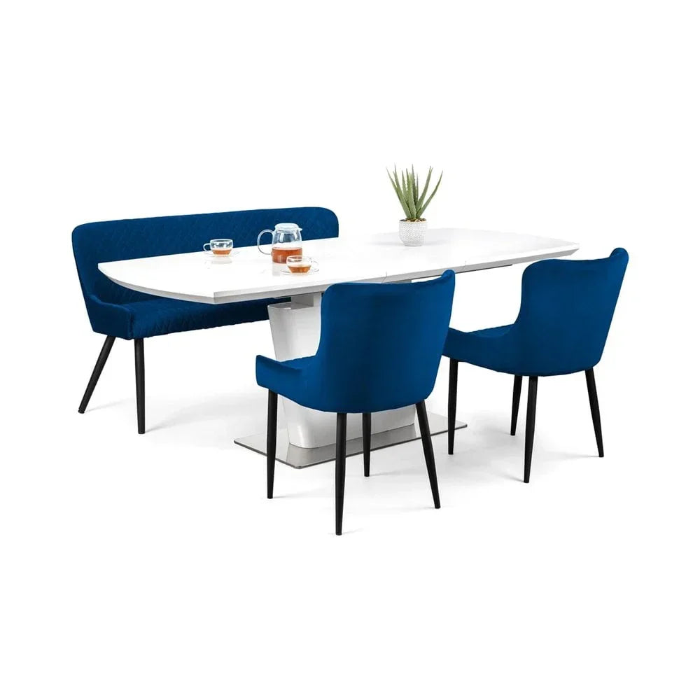 White dining table set with blue velvet bench and chairs, black legs, tabletop decor