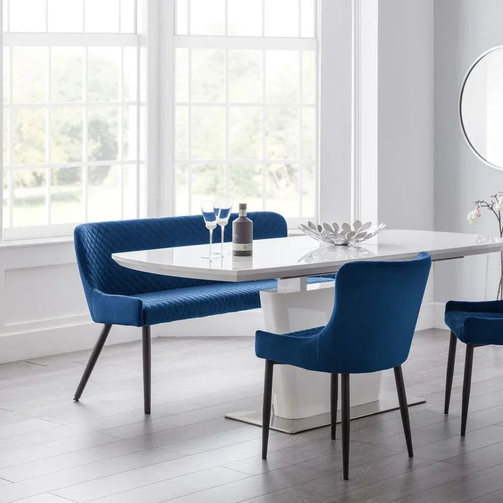 Modern white dining table set with blue velvet chairs and bench in bright room
