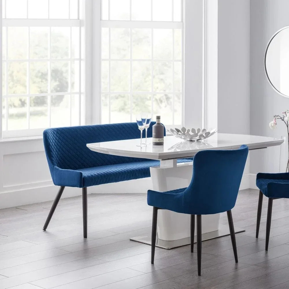 Modern white dining table with blue velvet chairs and bench in bright dining room