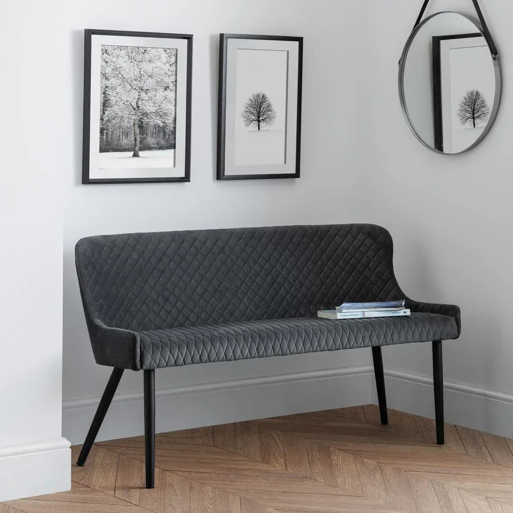 Grey quilted velvet bench with black metal legs in modern room with wood floor