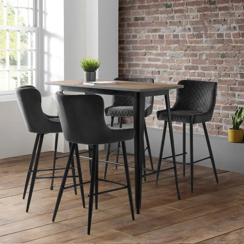 Industrial bar table with black upholstered bar stools in a modern dining room setting