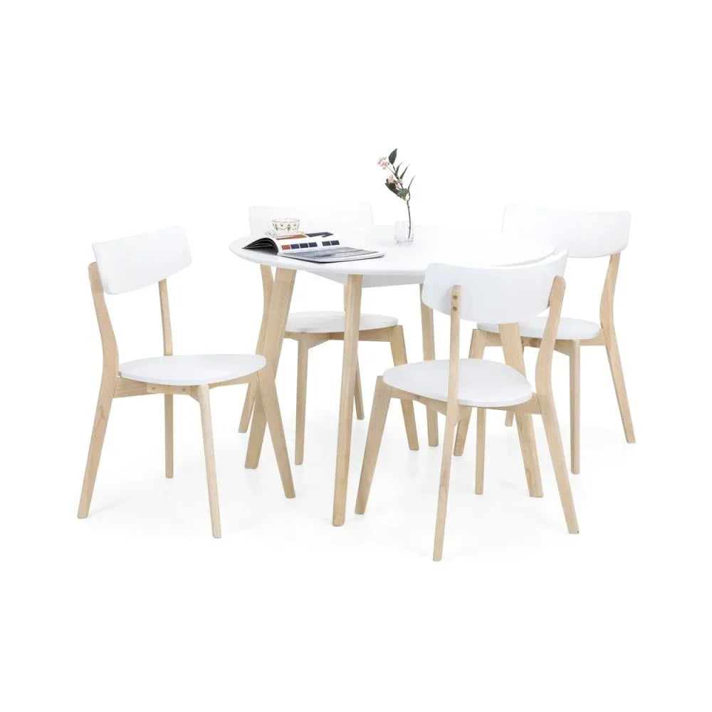 White dining table with four matching chairs, light wood legs, set arranged with minimal decor