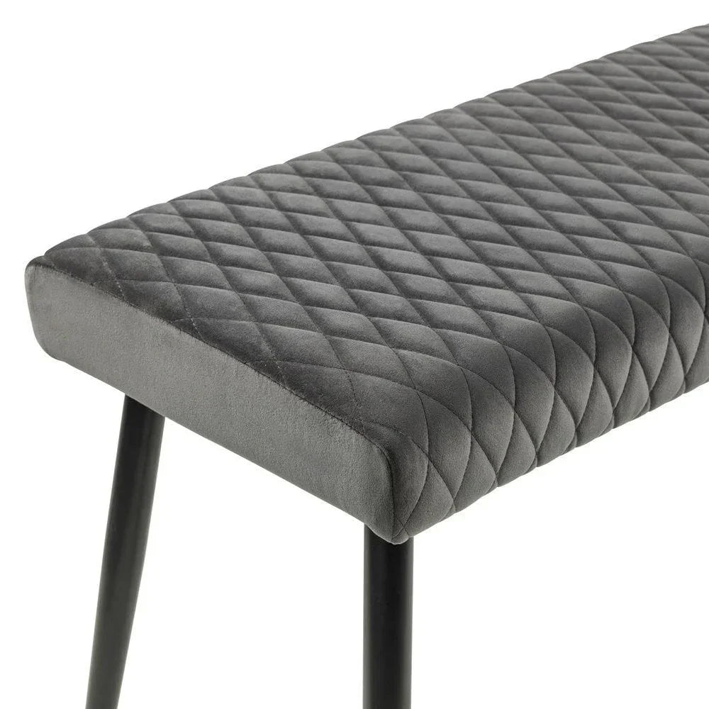 Grey velvet dining bench with diamond quilted seat and black metal legs, angled side view
