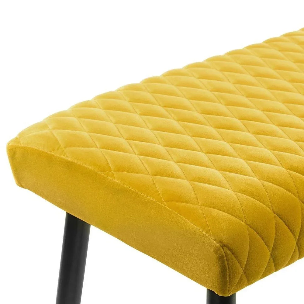 Yellow velvet bench seat with diamond quilted pattern and black legs, close-up view