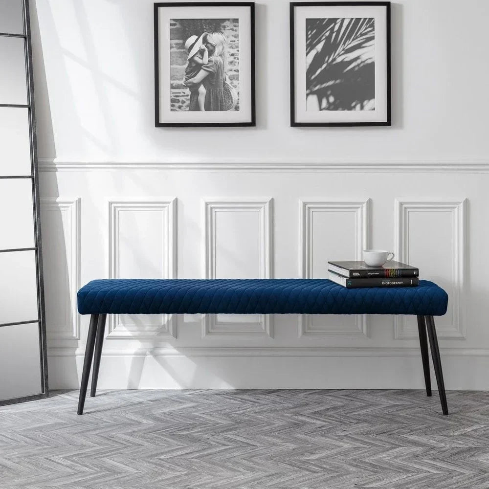 Blue velvet bench with black legs in modern hallway, books and cup placed on one end