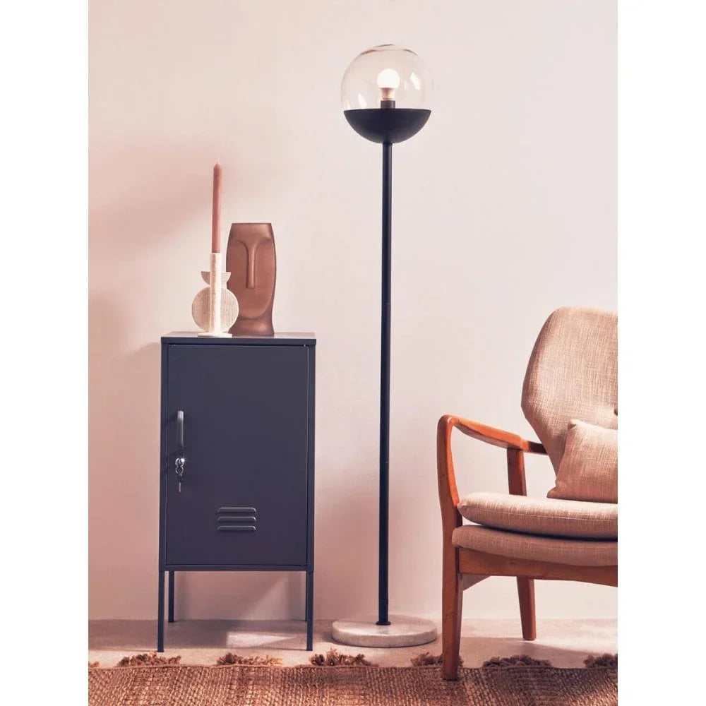 Modern storage cabinet with decor beside glass globe floor lamp and armchair
