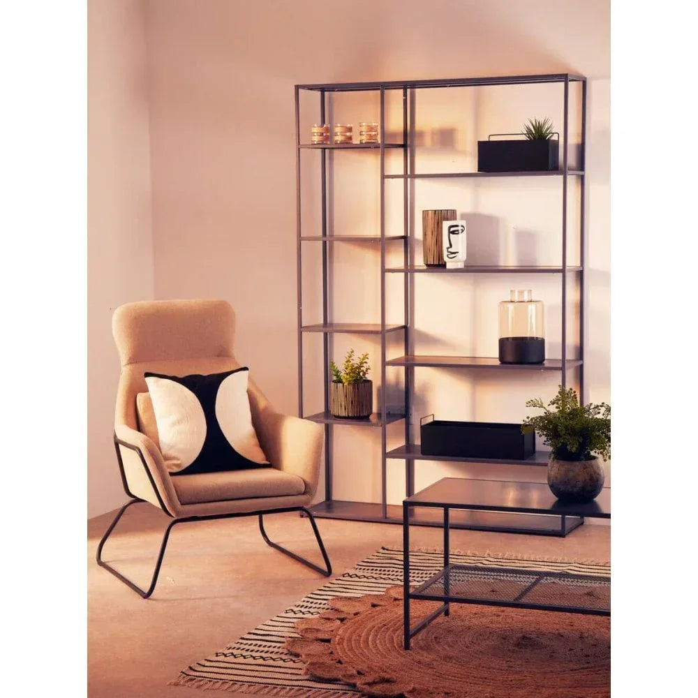 Beige accent chair with black and white cushion next to modern metal bookcase and coffee table