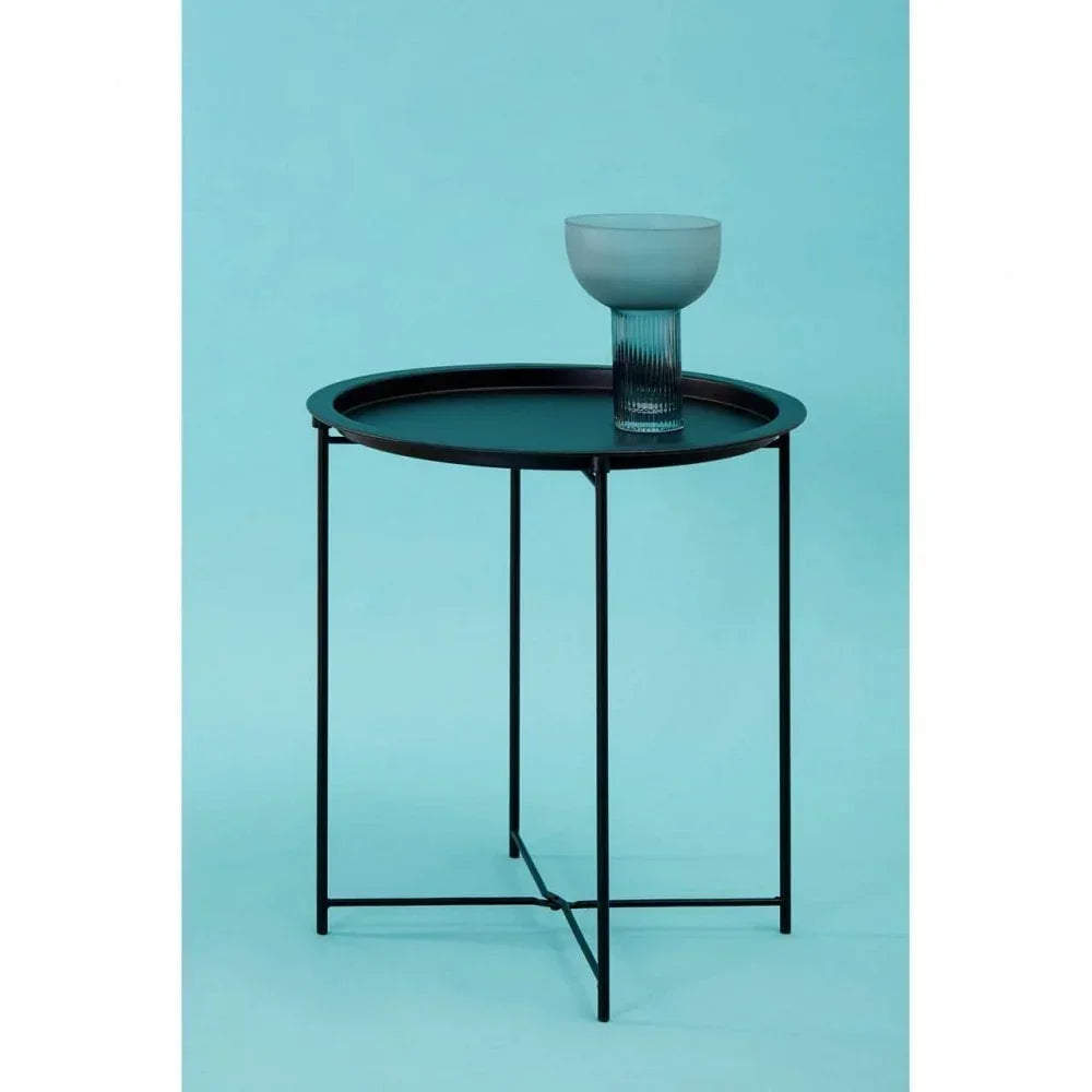 Round black metal side table with slim legs and ribbed glass on top against blue background