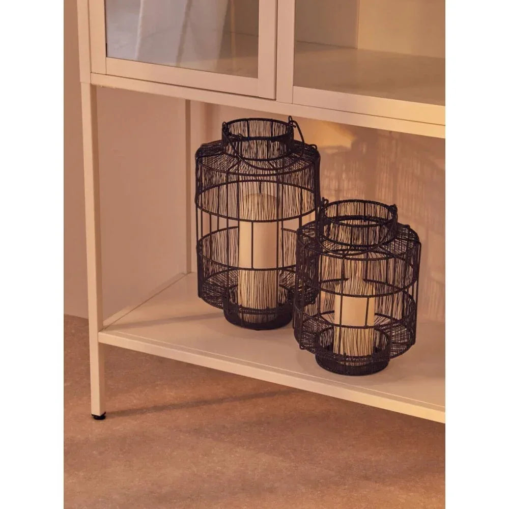 Black metal candle lanterns with pillar candles on shelf under white cabinet