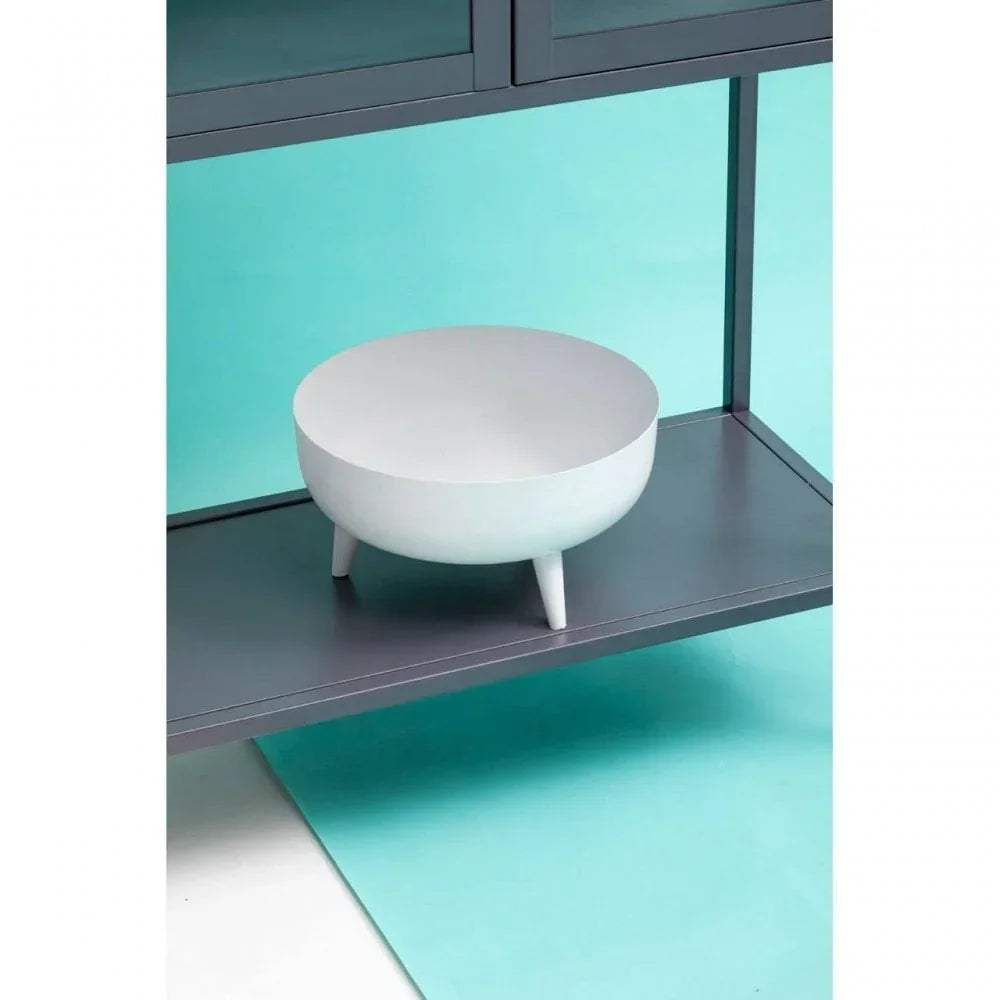 White ceramic decorative bowl with three legs on grey shelf against teal background