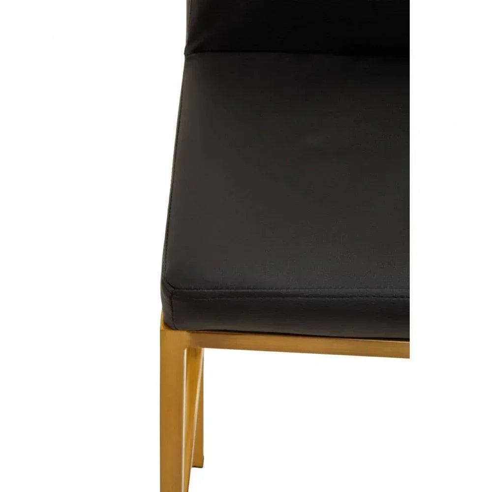 Black faux leather dining chair seat with gold metal frame, partial close-up view
