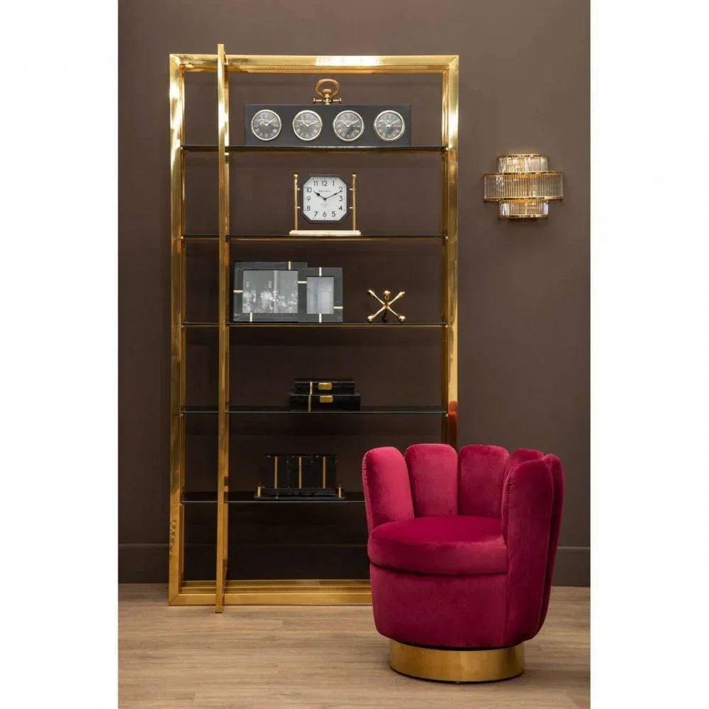 Gold metal shelving unit with clocks and decor, velvet pink accent chair on wood floor