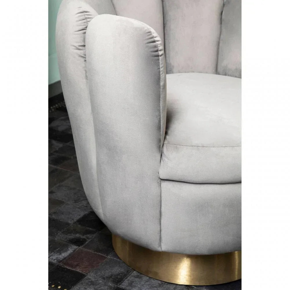 Grey velvet armchair with gold base close-up on dark tiled floor