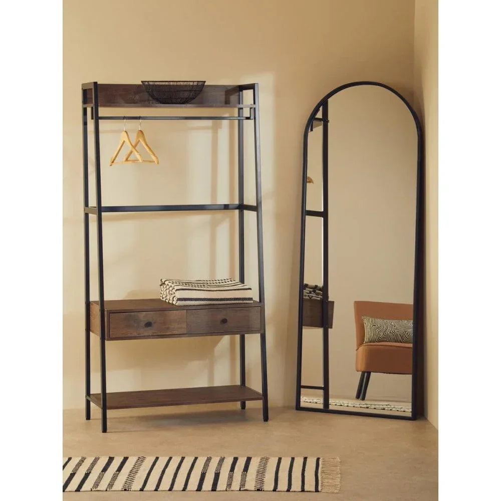 Industrial wooden clothes rail with drawers beside black-framed arched full length mirror