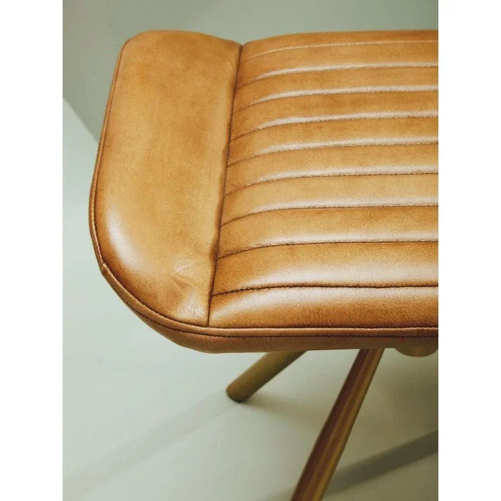 Close-up of tan leather dining chair seat with stitched horizontal lines and wooden legs
