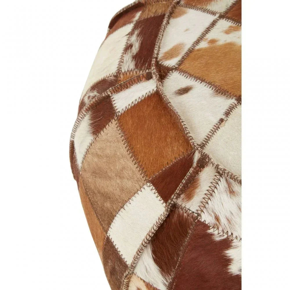 Patchwork cowhide pouffe with brown and white stitched square panels, close-up view