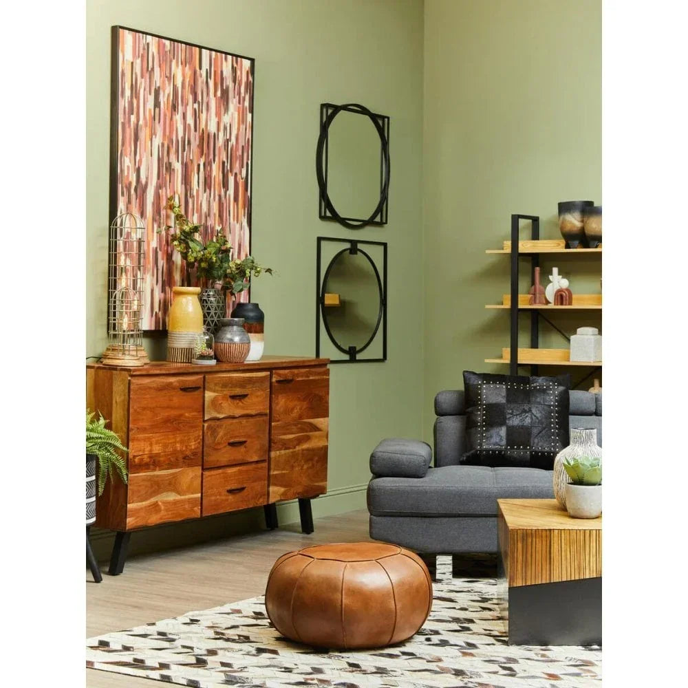 Mid-century wood sideboard with vases beside grey sofa and leather pouffe in living room