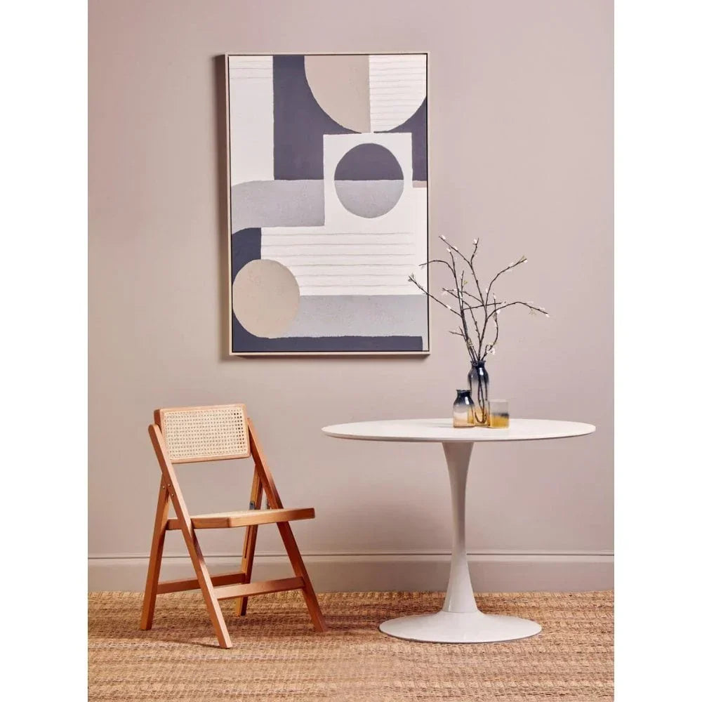 Wooden folding chair beside round white dining table with branch vase in modern room