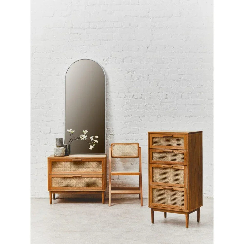 Rattan bedroom furniture set with wooden chest of drawers, chair, and arched wall mirror