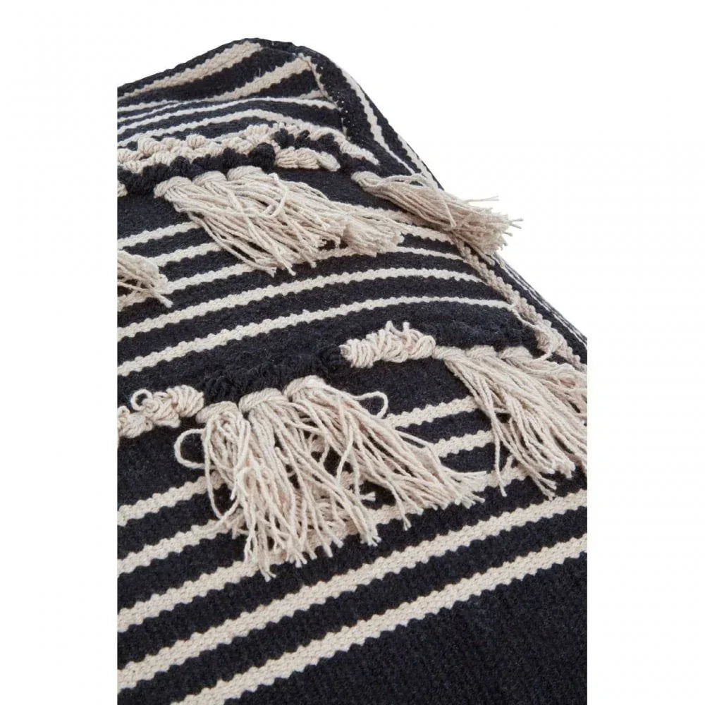 Striped cushion cover with black and cream tassels, close-up of textured fabric