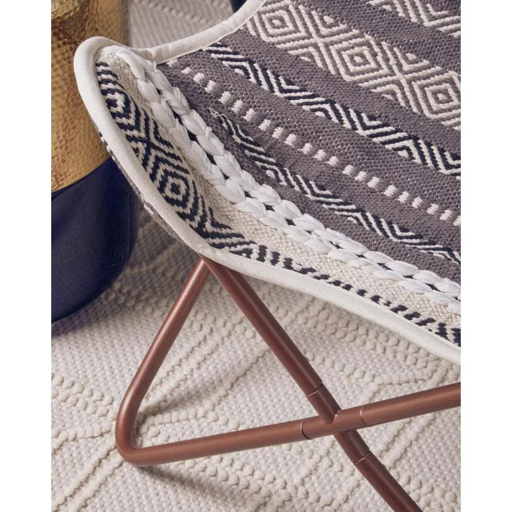 Patterned fabric accent chair with copper frame on textured rug