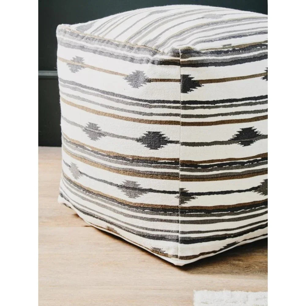 Geometric patterned fabric pouffe in neutral tones on wooden floor