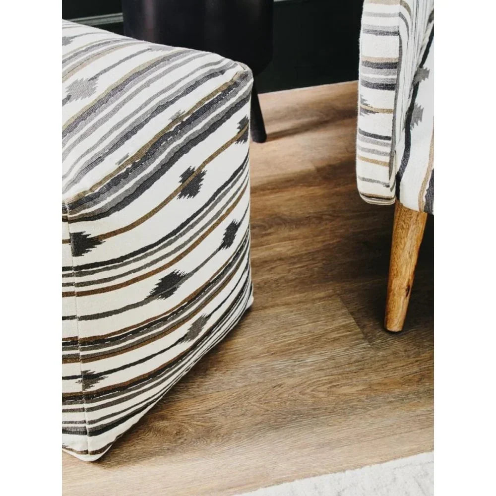 Patterned fabric pouffe ottoman and armchair on wooden floor