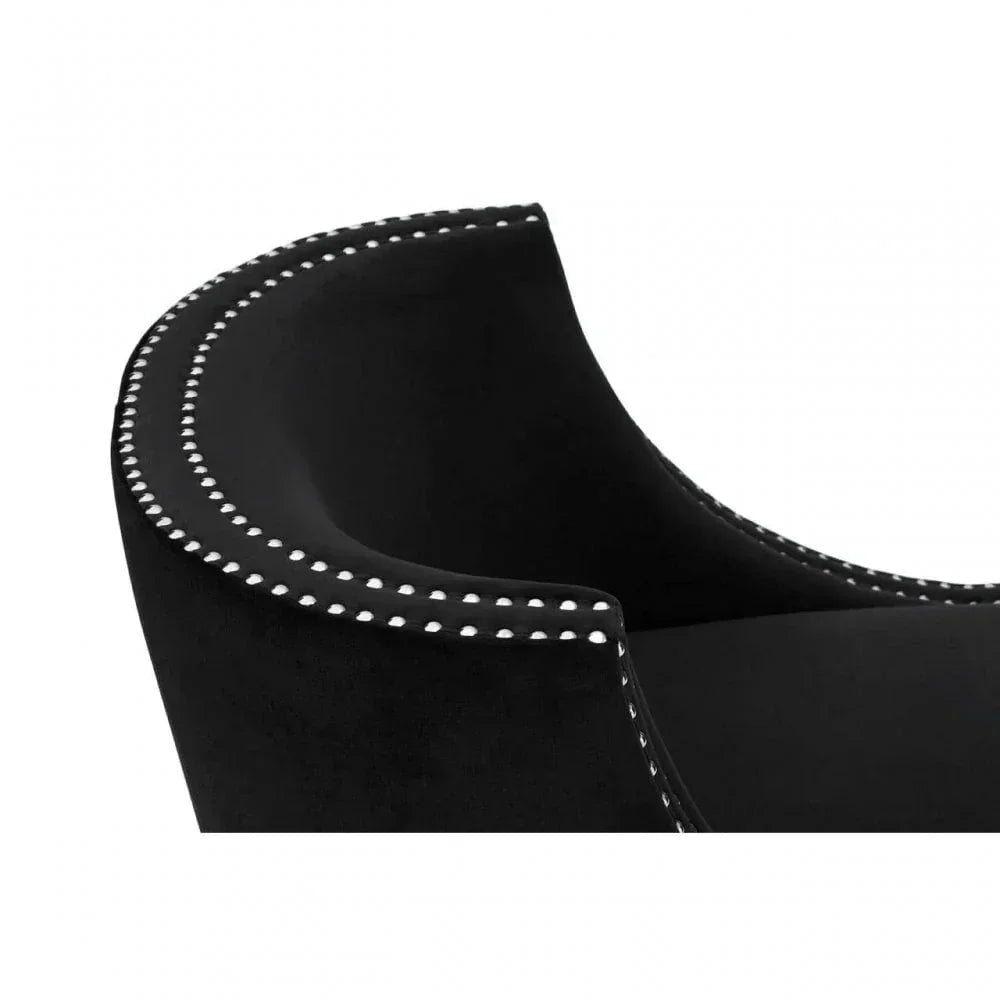 Black velvet armchair with silver studded trim, close-up of curved backrest and detail