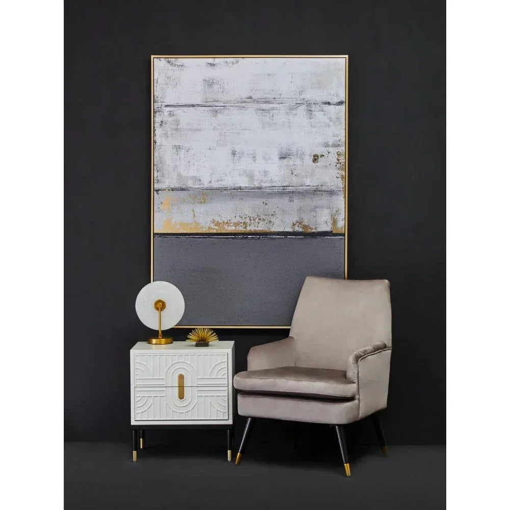 Velvet accent chair with gold legs beside white geometric side table and abstract wall art