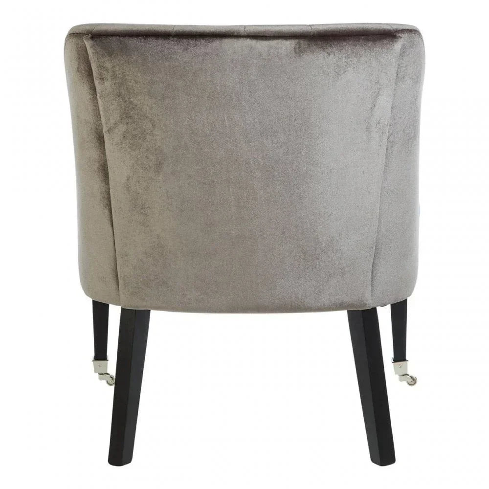 Grey velvet accent chair rear view with black wooden legs and silver castor wheels