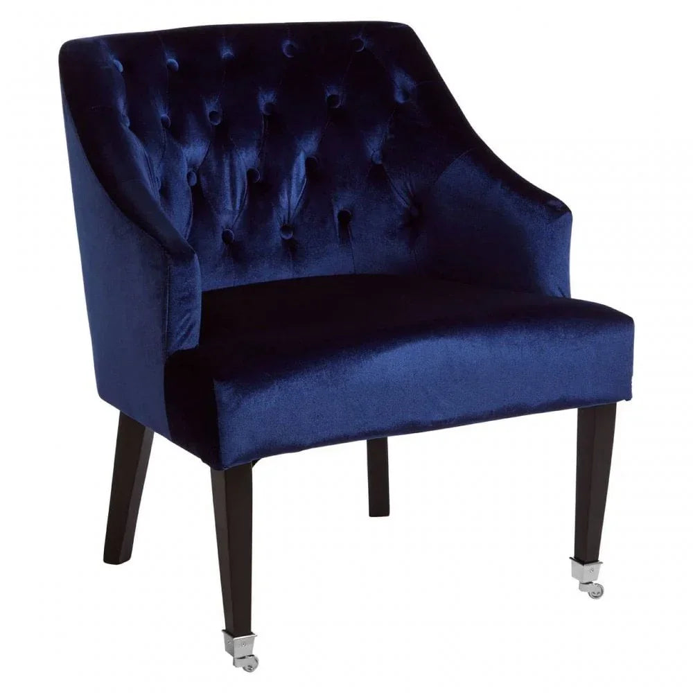 Navy blue velvet accent chair with button tufted back and dark wooden legs on casters
