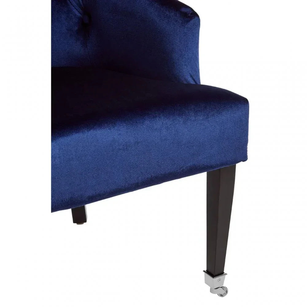 Blue velvet chair corner showing dark wooden legs and metal caster detail