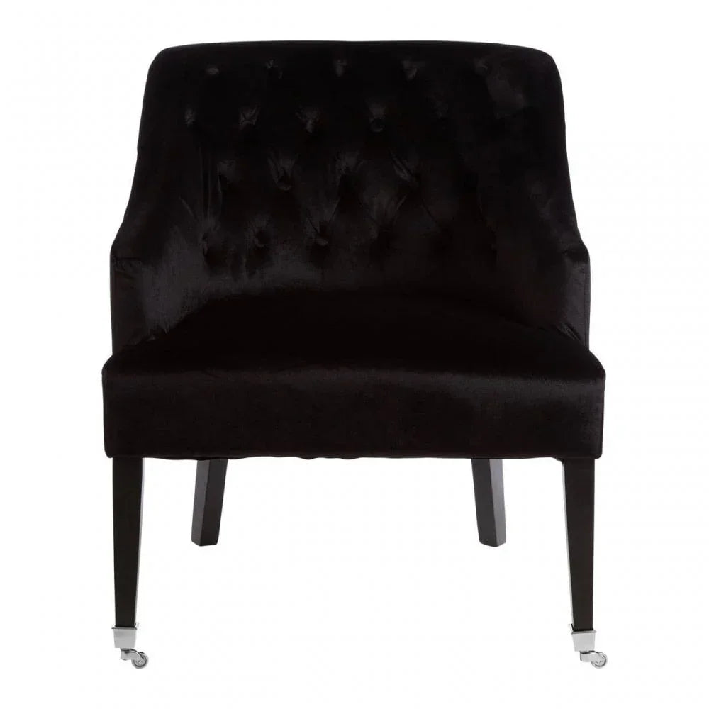 Black velvet accent chair with button-tufted backrest and front leg casters, front view