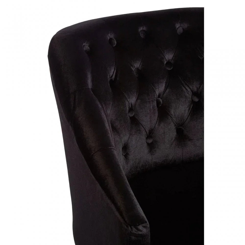 Close-up of black velvet armchair with deep button tufted backrest