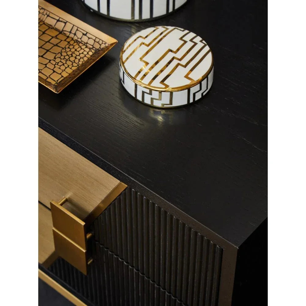 Black wooden sideboard with gold handles, decorative tray and round patterned jar on top