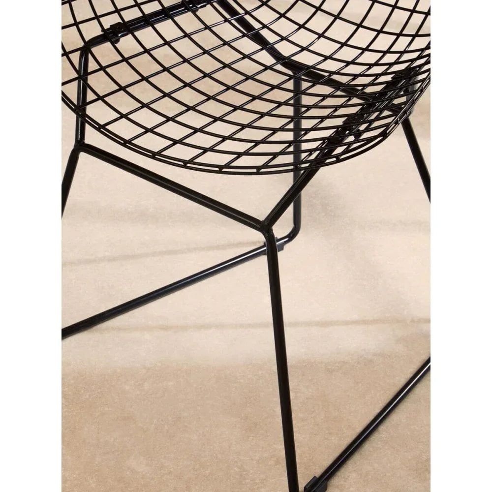 Black wire dining chair with modern metal frame on beige floor, close-up seat and legs