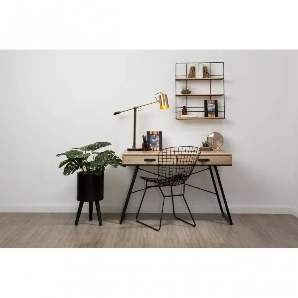 Modern home office desk with black wire chair, gold lamp, and wall shelves