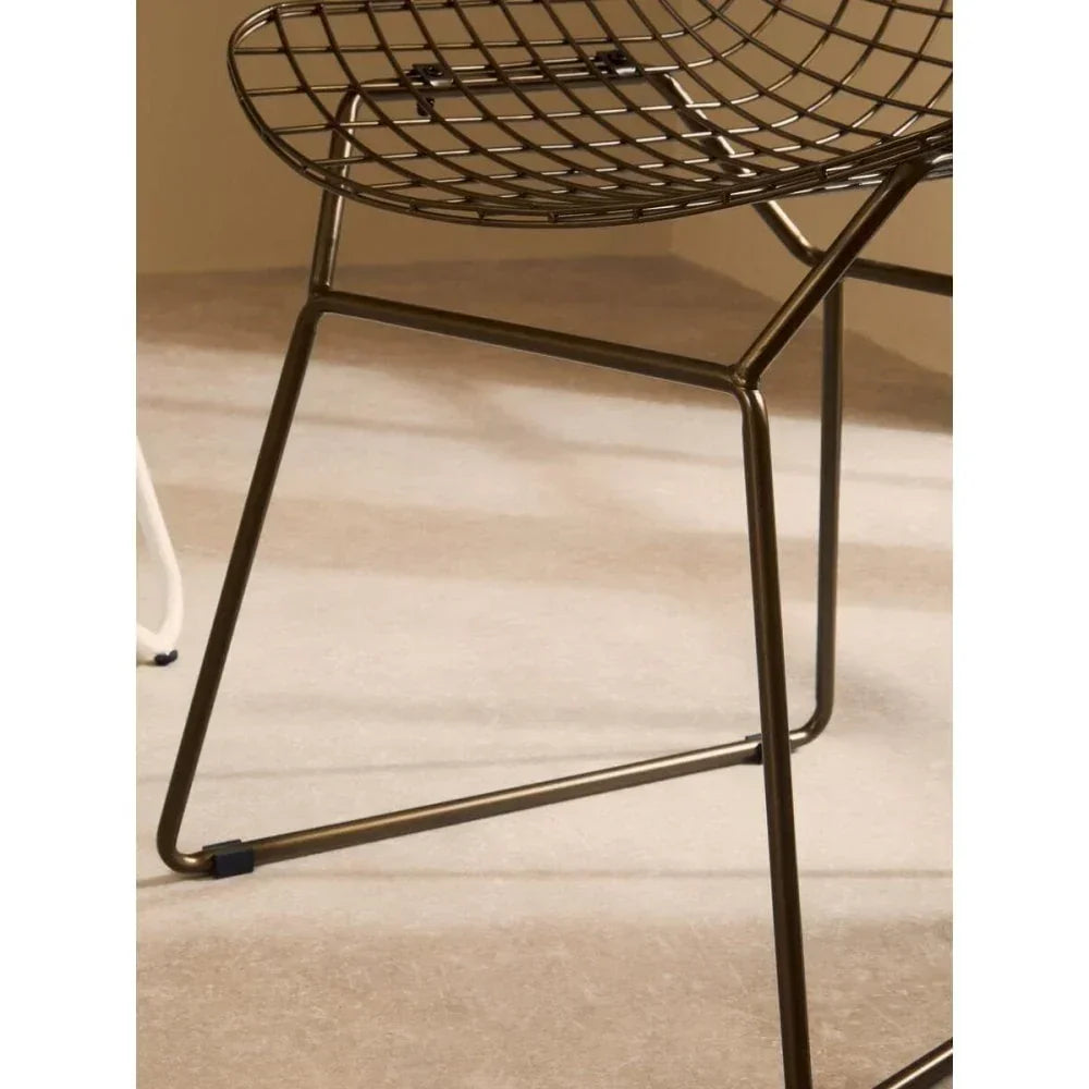 Close up of metal wire chair with geometric legs on beige floor